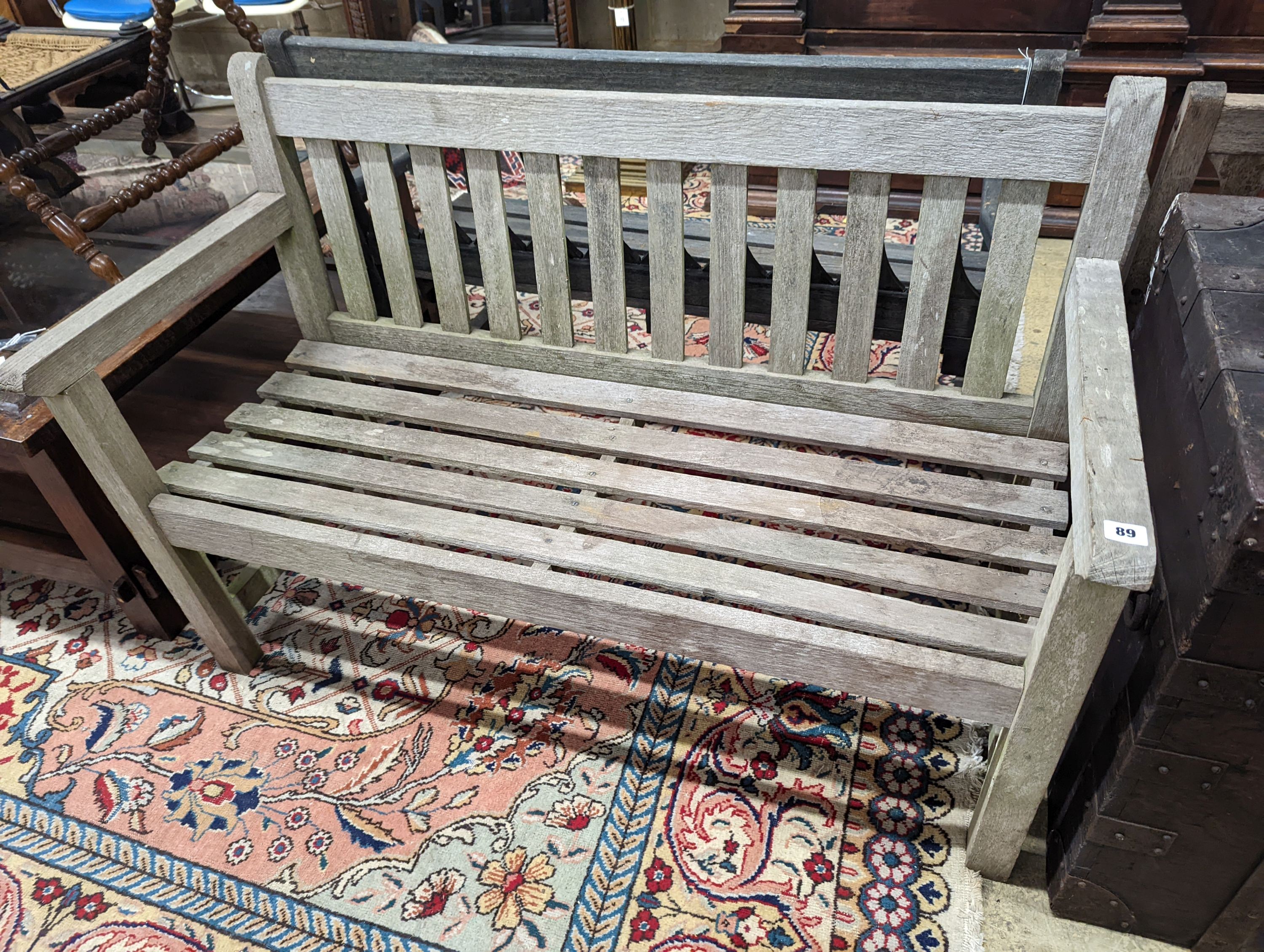 A weathered teak slatted garden bench